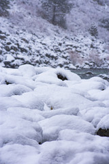 Fototapeta na wymiar Snow Covered Rocks Lining a River