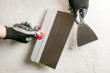 The builder holds a spatula in his hand. The concept of renovation, repair. DIY