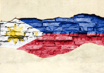 National flag of Philippines on a brick background. Brick wall with partially destroyed plaster, background or texture.