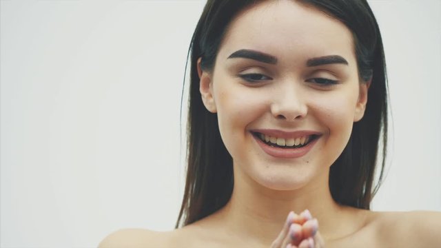 The beauty of a woman with perfect makeup makes a kiss gesture. Close-up portrait of a beautiful cute charming happy girl, having a beautiful body by sending an air kiss. Isolated on a white