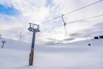 Empty Ski Lift in a Snowy Slope in the Alps on a Partly Cloudy Winter Day