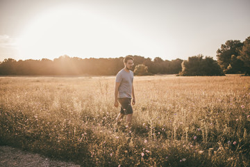 Mann wandert durch ein Feld im Sommer im Gegenlicht