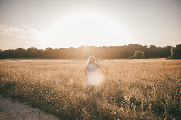 Frau genießt den Sommer beim Spaziergang durch ein Feld