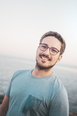 Mann mit Brille lächelt in die Kamera am Strand