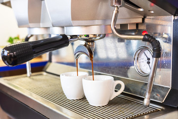 Espresso coffee machine brewing two shots in white cups, professional Italian equipment at restaurant or bar counter, close-up