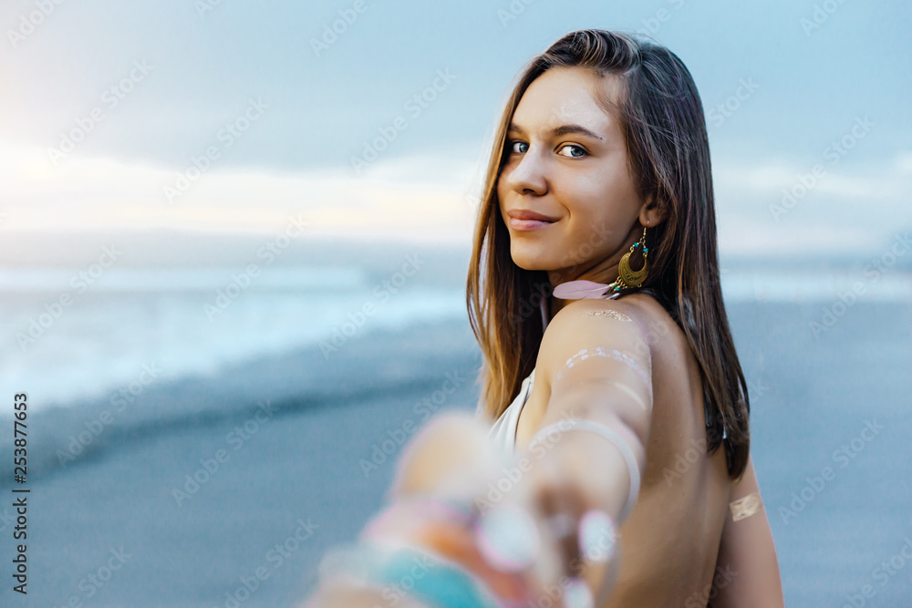 Wall mural Young girl with silver tattoo and boho jewelry on sunset