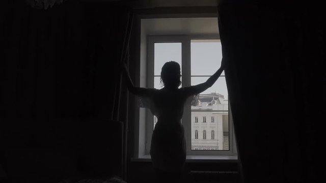 Young businesswoman unveil curtain and looking out of window.