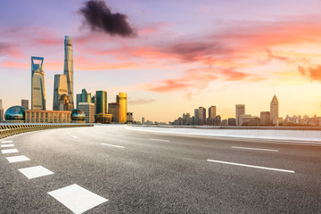 Obraz premium Empty asphalt road through Shanghai business district at sunset
