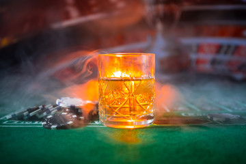 gambling, fortune, game and entertainment concept - close up of casino chips and whisky glass on table
