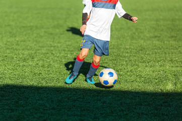 Obraz premium Football training soccer for kids. Boy runs kicks dribbles soccer balls. Young footballers dribble and kick football ball in game. Training, active lifestyle, sport, children activity concept 