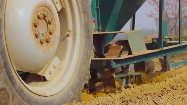 A tractor harrowing in the farm Soil, Low Angle Close up view of big Tyre of the tractor