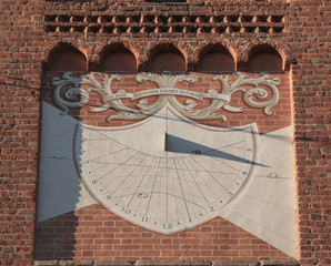 sundial on the brick facade of an ancient church marks 4.30 PM
