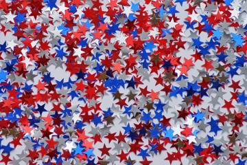 Red white blue shiny confetti stars on grey  background, tricolor concept, independence and freedom day USA