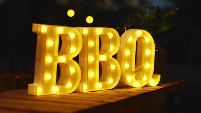 Glowing yellow BBQ sign lit up outside at night in the Caribbean