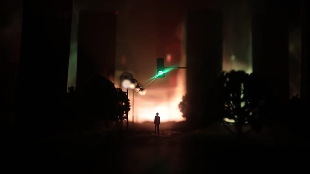 Artwork decoration. A man standing on a road of burnt up city. Apocalyptic view of city downtown as disaster film poster concept. Night scene. City destroyed by war. Selective focus