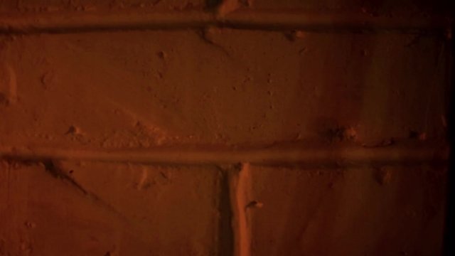 faint flickering orange fire lights lighting up a bricks wall