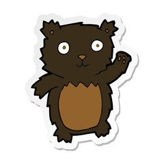 sticker of a cartoon waving black bear cub