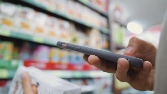 Female Customer Scanning Product Bar Code in the Shop Using Mobile Phone App. Digital Shopping Future Gadget Consumerism Concept. 4K Slowmotion.