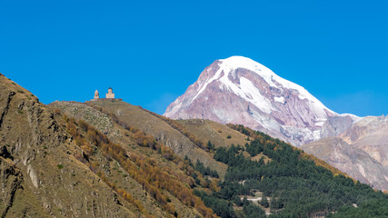 Mount Kazbek (Mkinvartsveri) and Gergeti church at sunny day. Caucasus mountains