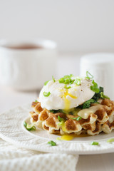 Waffles with poached egg and flowing yolk, cheese and spinach.