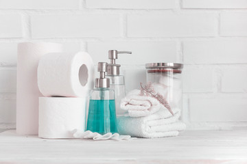 Part of spa interior. Cotton napkins, cotton pads, tissue, towels, soap and cosmetic products on wooden table. White background and table. Copy space. Selective focus.
