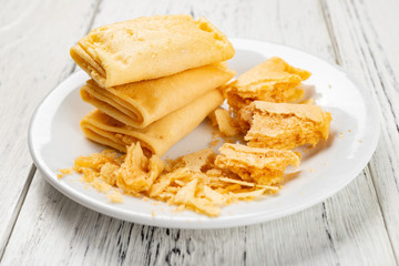 traditional Chinese egg roll called TuWeiDanJuan with some broken bits on white wood background