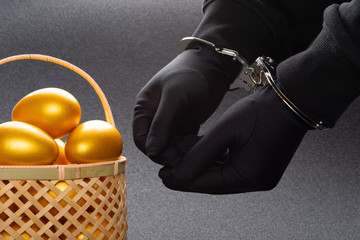 arrested man in handcuffs in front of a basket with gold eggs
