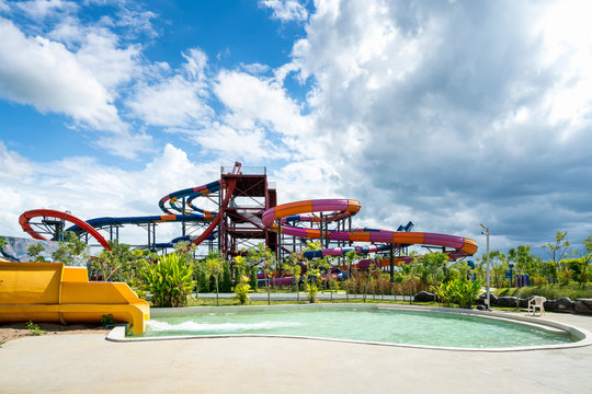 colorful large slider and pool at amusement water park in cloudy and blue sky day