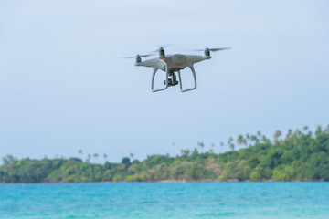 Fototapeta na wymiar flying drone with blue sky ocean island background