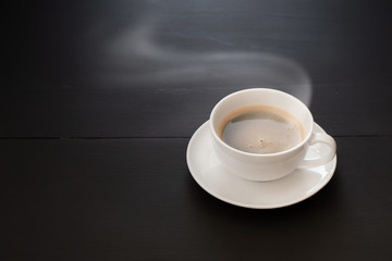 Black coffee in White ceramic coffee mugs on a black wooden table.