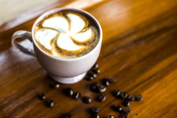 cup of coffee with cream on wooden background