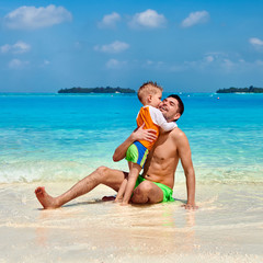 Toddler boy on beach kissing father