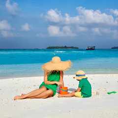 Woman in green dress with three year old boy on beach