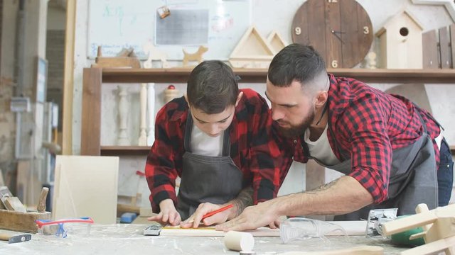 profession, carpentry, woodwork and family concept - carpentery masterclass for little children and their fathers to share basic knowledge of working with wood.