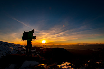 Red sunset and the silhoute of  photographer enthusiast stay on cliff and thinking..