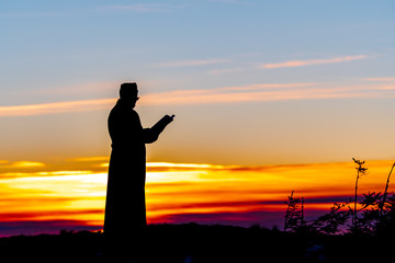 Priest silhoute reading in the sunset light, Romania