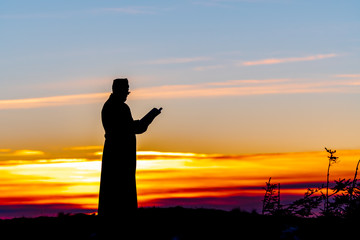 Priest silhoute reading in the sunset light, Romania