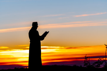 Priest silhoute reading in the sunset light, Romania
