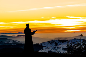 Priest silhoute reading in the sunset light, Romania
