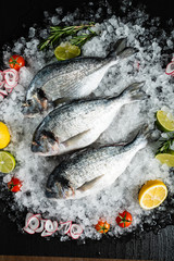 Fresh raw dorado fish and food ingredients on table