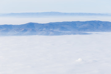 Fototapeta premium Fog filling a valley in Umbria (Italy), with layers of mountains and hills, various shades of blue