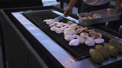 Grilled scallop on a charcoal grill by the beach.
