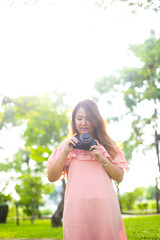 Photo of Female photographer holding retro photo camera at park or natural landscape background