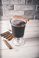 Mulled wine in a beautiful glass. Winter warming drink. Hot mulled wine on the wooden table. Glass of mulled wine with spices. 