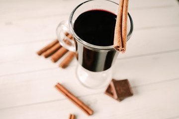 Mulled wine in a beautiful glass. Winter warming drink. Hot mulled wine on the wooden table. Glass of mulled wine with spices. 