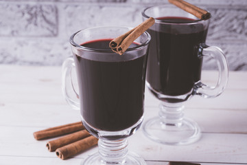 Mulled wine in a beautiful glass. Winter warming drink. Hot mulled wine on the wooden table. Glass of mulled wine with spices. 
