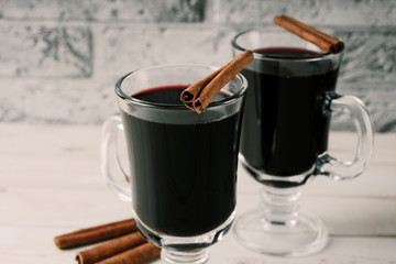 Mulled wine in a beautiful glass. Winter warming drink. Hot mulled wine on the wooden table. Glass of mulled wine with spices. 