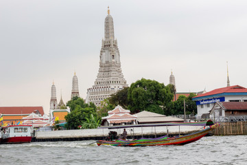 Naklejka premium Long-tail boat passing Wat Arun Ratchawararam Ratchaworawihan