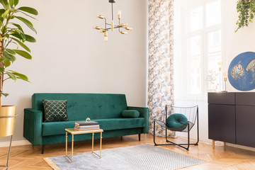 Stylish decor of living room with design green velvet sofa, plants, design commode, accessories,...
