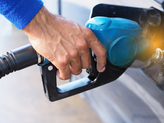Closeup hand of man pumping gasoline fuel in car at gas station.